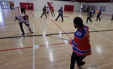 adults in gym playing floor hockey