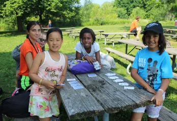 Group of female campers playing cards at picnic table