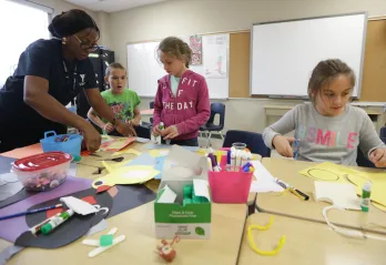 Educator with children crafting at table