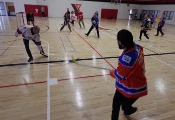 adults in gym playing floor hockey