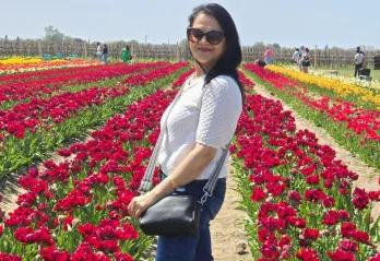 women stands in field of red tulips