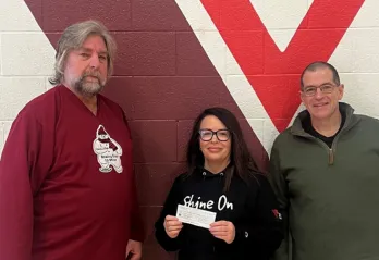 two men and a women stand in font of YMCA logo