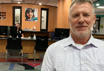  Smiling Older man sits in front of membership desk