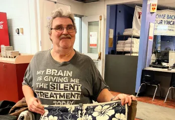 Older man in front of Y membership desk holding shorts 