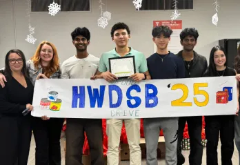 high school students hold banner that says HWDSB 2025 Food Drive