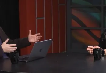 Two people speaking behind a desk