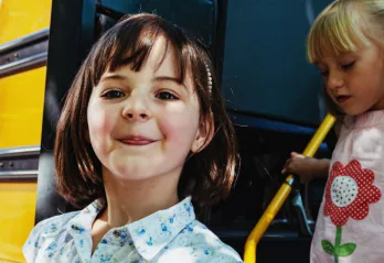 young girls get off yellow bus to summer camp