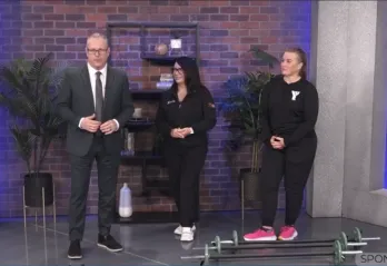 Man and two women in a news segment standing in front of small barbells 
