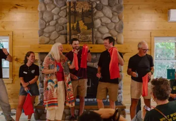 Group of people holding pieces of a red ribbon and scissors 