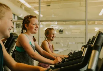 three girls on treadmills smiling