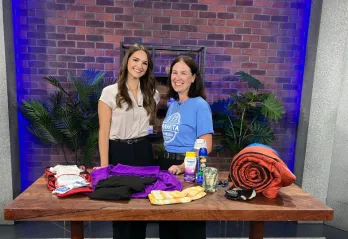 Two women smiling behind a table of camping supplies