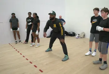 Coach showing youth how to play handball in a handball court
