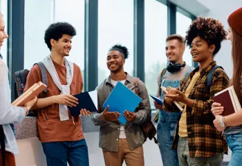 6 young people standing in a  circle talking, smiling.