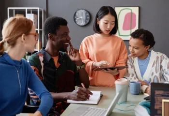 Four youth sitting inside at a table discussing career opportunities, smiling.