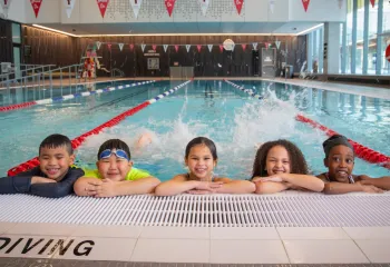 kids kicking water at side of pool and smiling