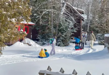 Family walking through wintery scene with cabins in background