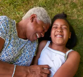 Two individuals laying on the grass smiling and laughing