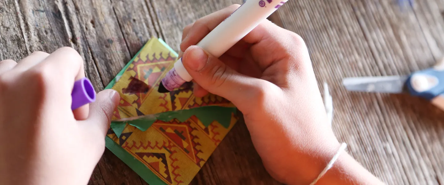 Close-up of hands making a craft with markers