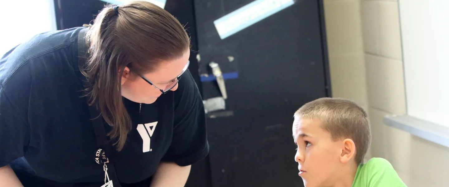Educator bent over speaking with seated child