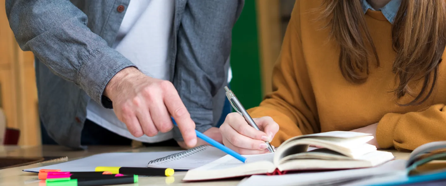 Two people reading a book together and discussing.