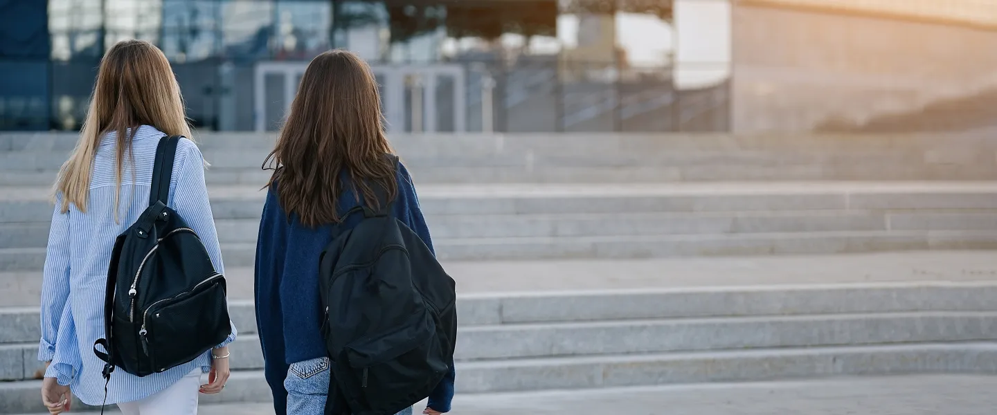 Two young people walking outside with backpacks
