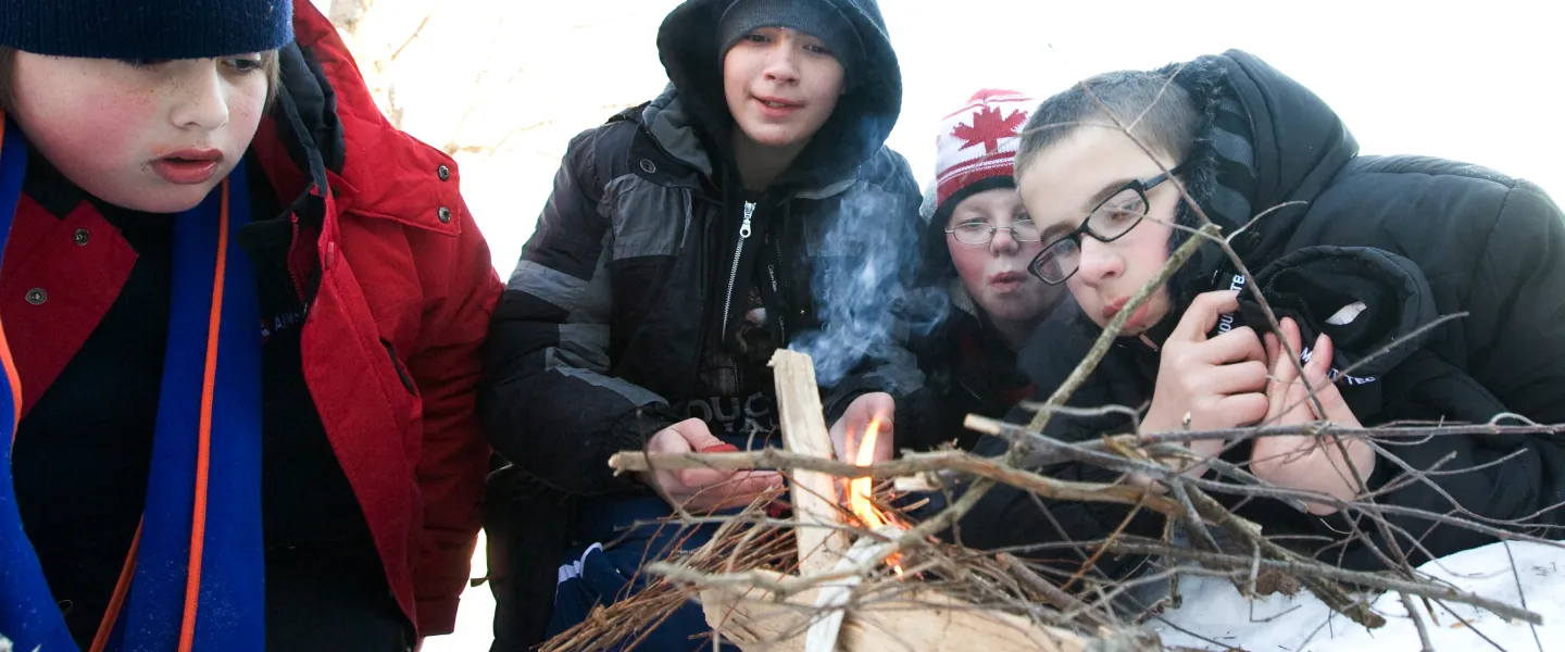Four boys build a small campfire