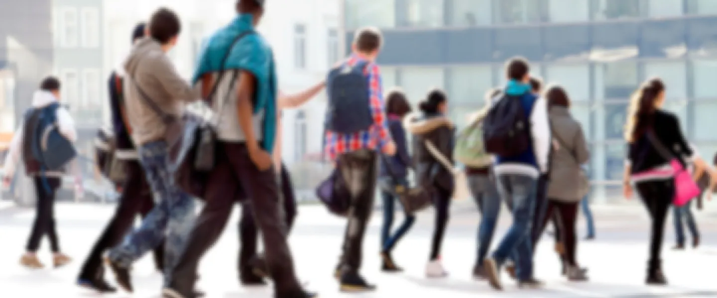 A blurry image of diverse young people outside walking away from the camera. You cannot see anyone's face.