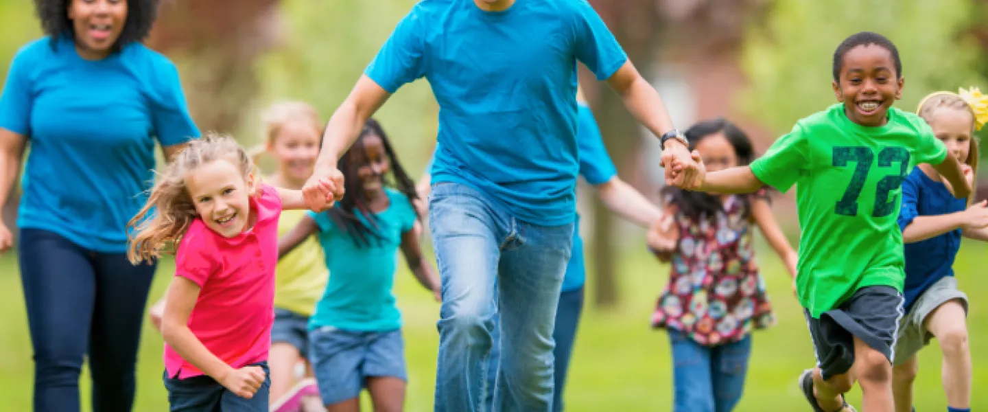 Group of individuals of all ages running and holding hands