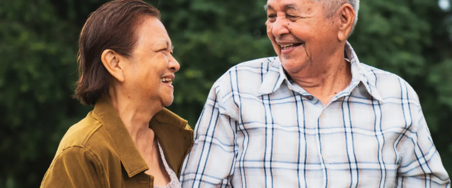 Two older individuals walking together and smiling