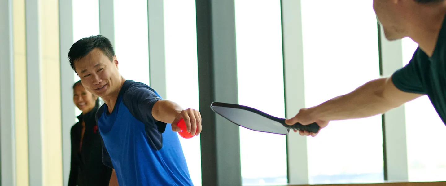 Two individuals playing Pickelball