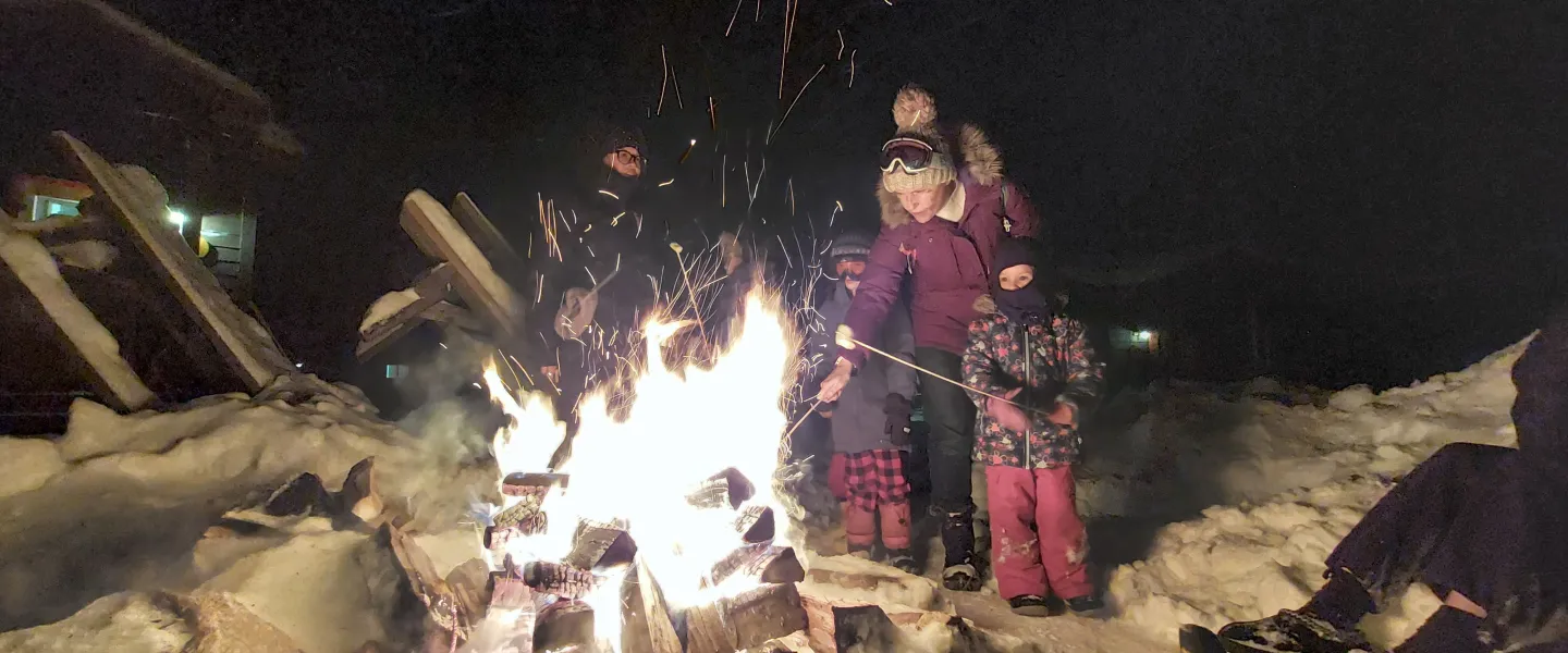 Family roasting marshmellows at fire in wintertime
