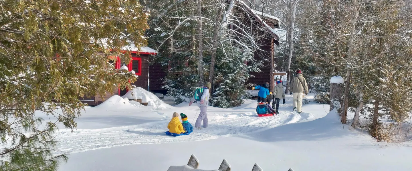 Family walking through wintery scene with cabins in background