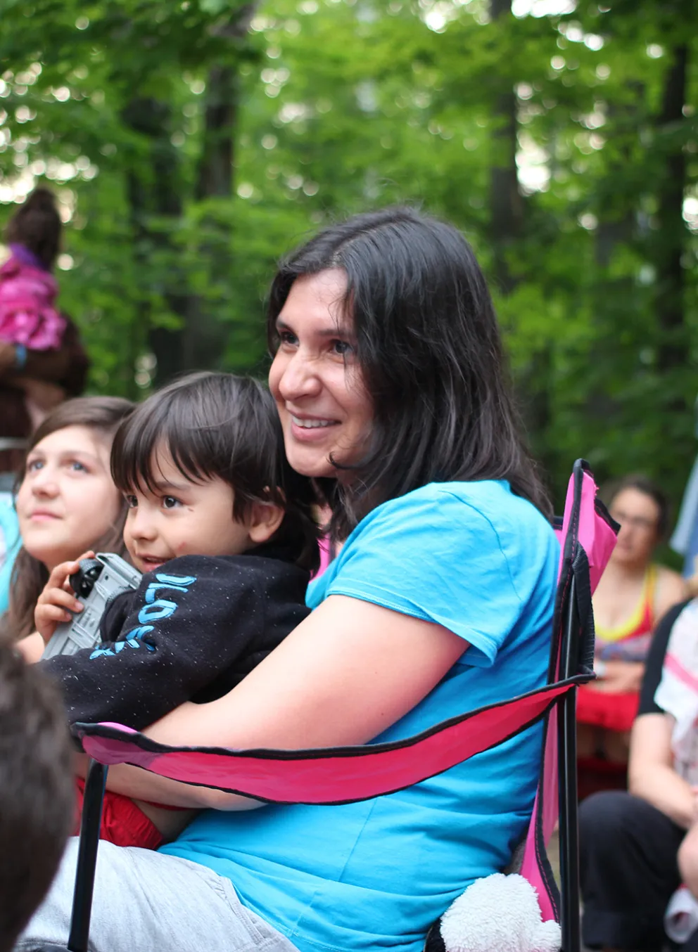 Mother and son sitting around group camp fire