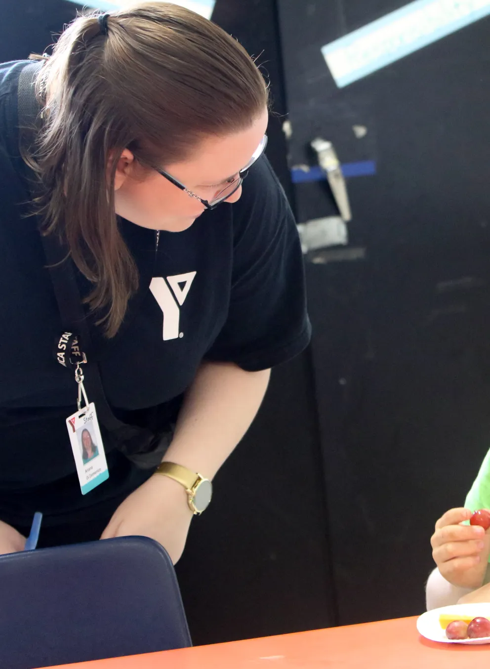 Educator bent over speaking with seated child