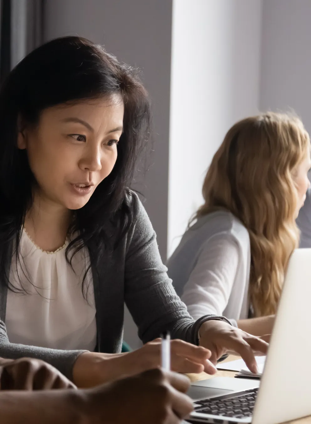 four people in two conversations, looking at laptops, talking professionally.