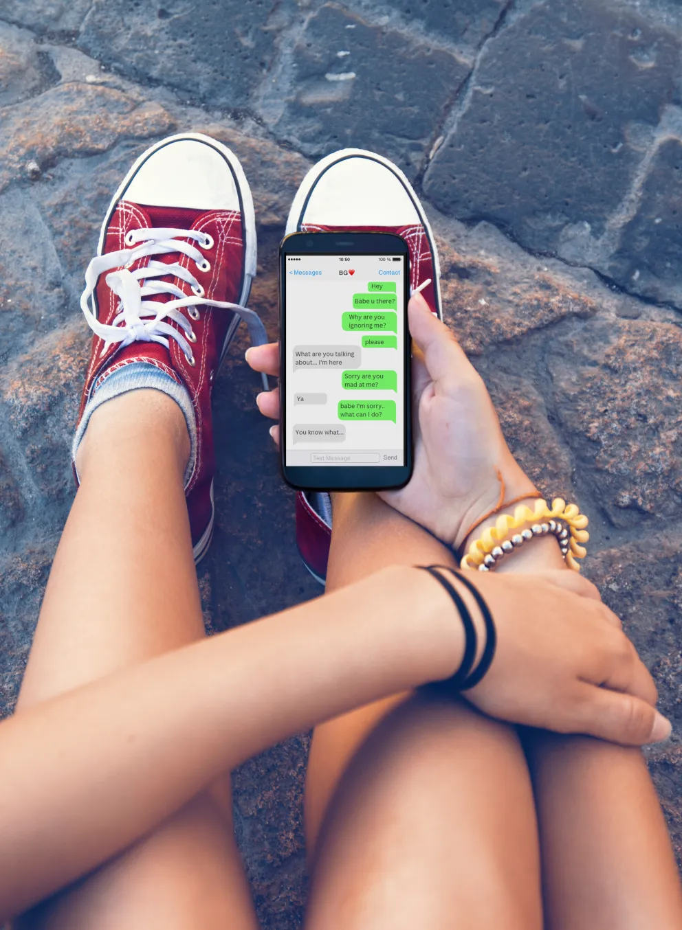 young person looking at phone. The phone screen shows text messages with someone who they are having an argument with.