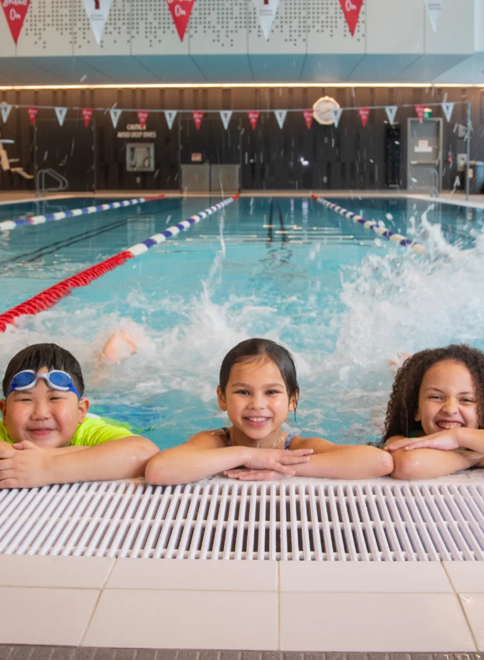 Five children in pool kicking feet and smiling