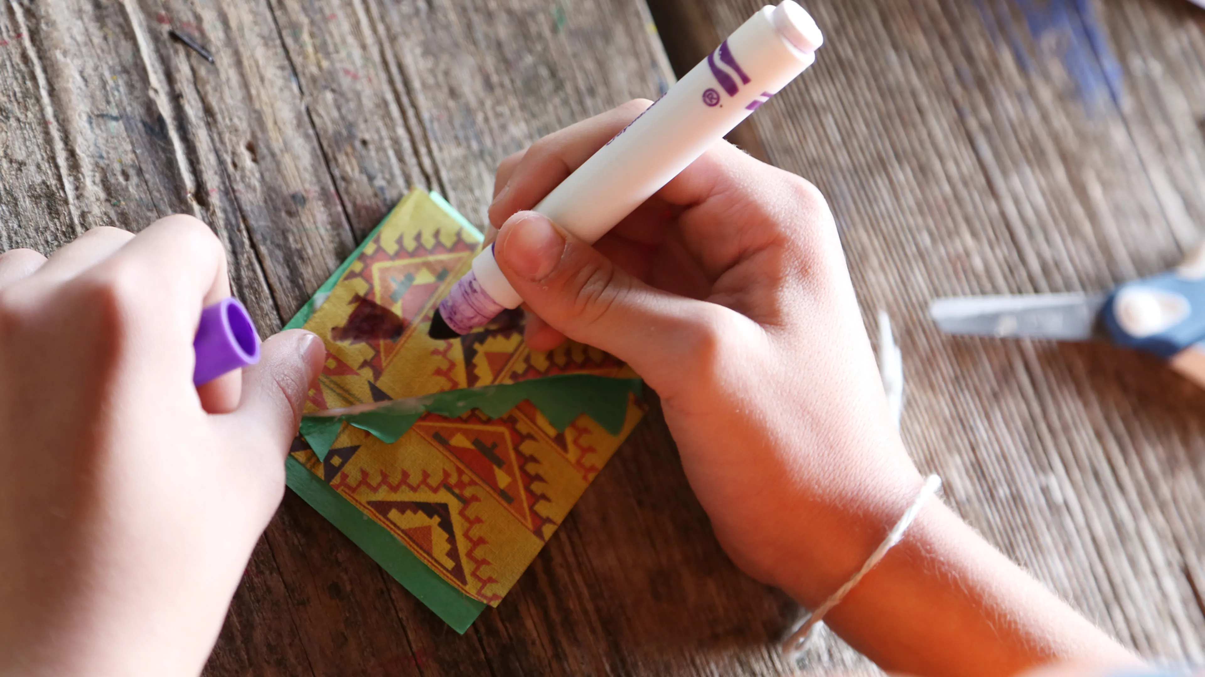 Close-up of hands making a craft with markers