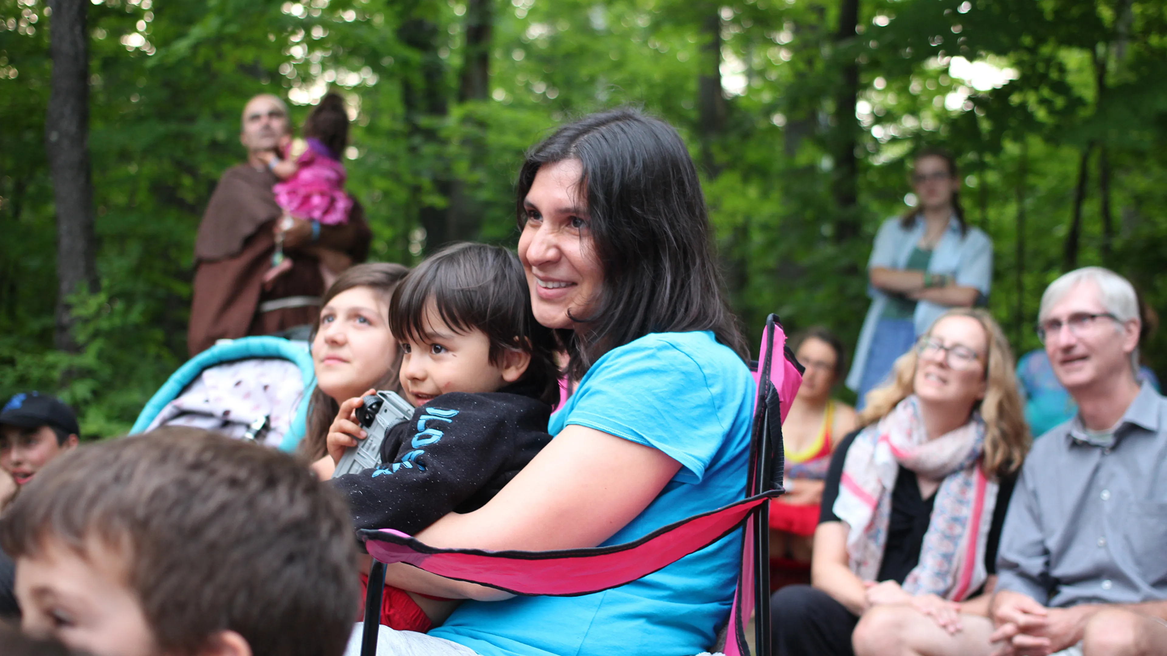 Mother and son sitting around group camp fire
