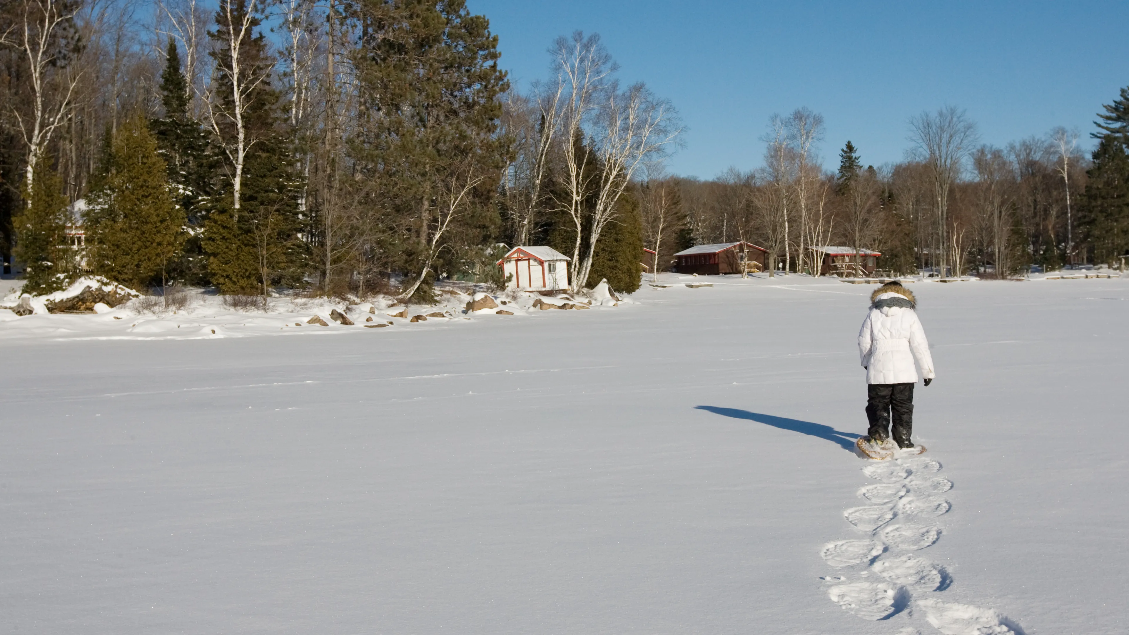 Snowshoer trekking across frozen lake