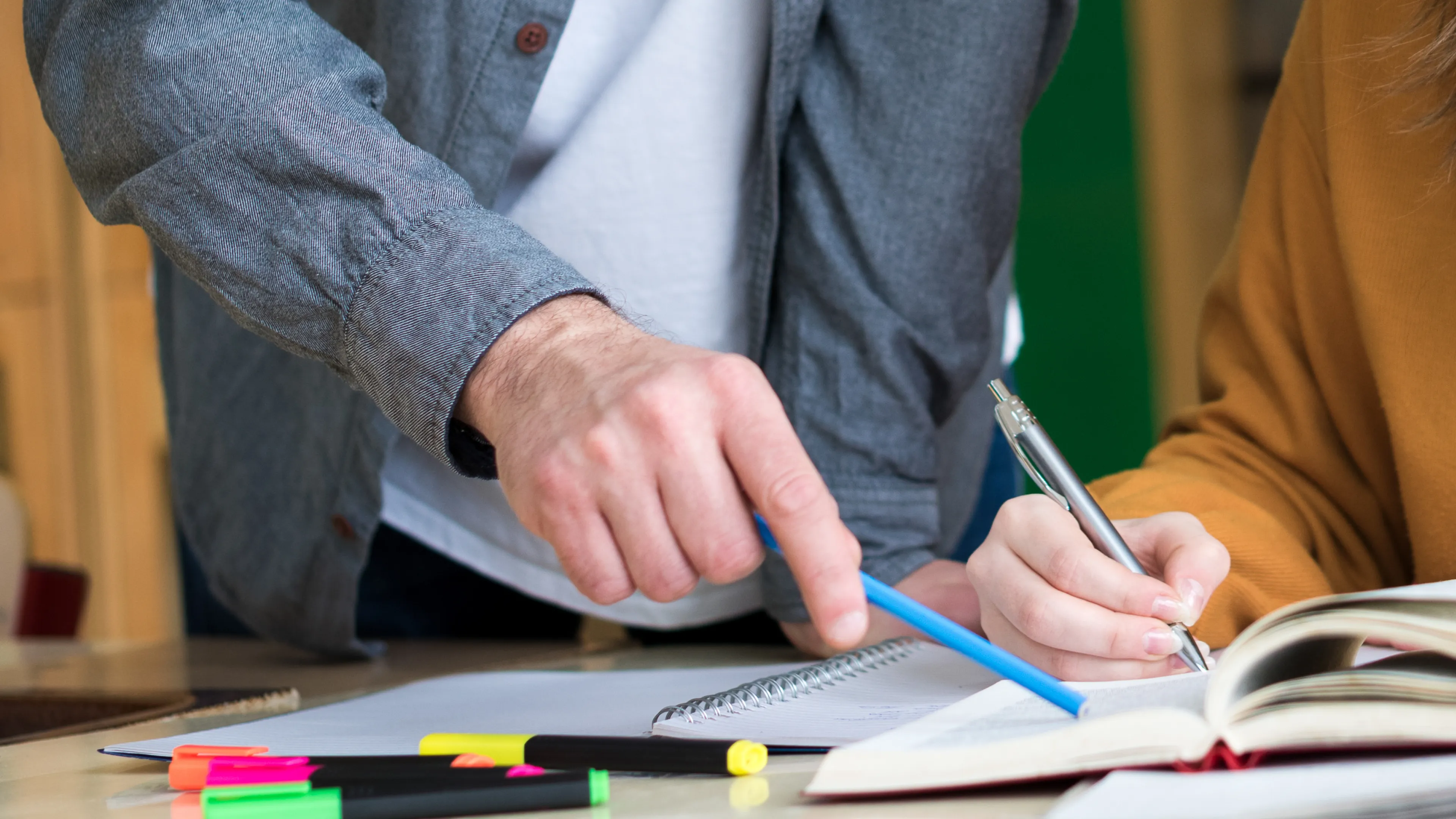 Two people reading a book together and discussing.