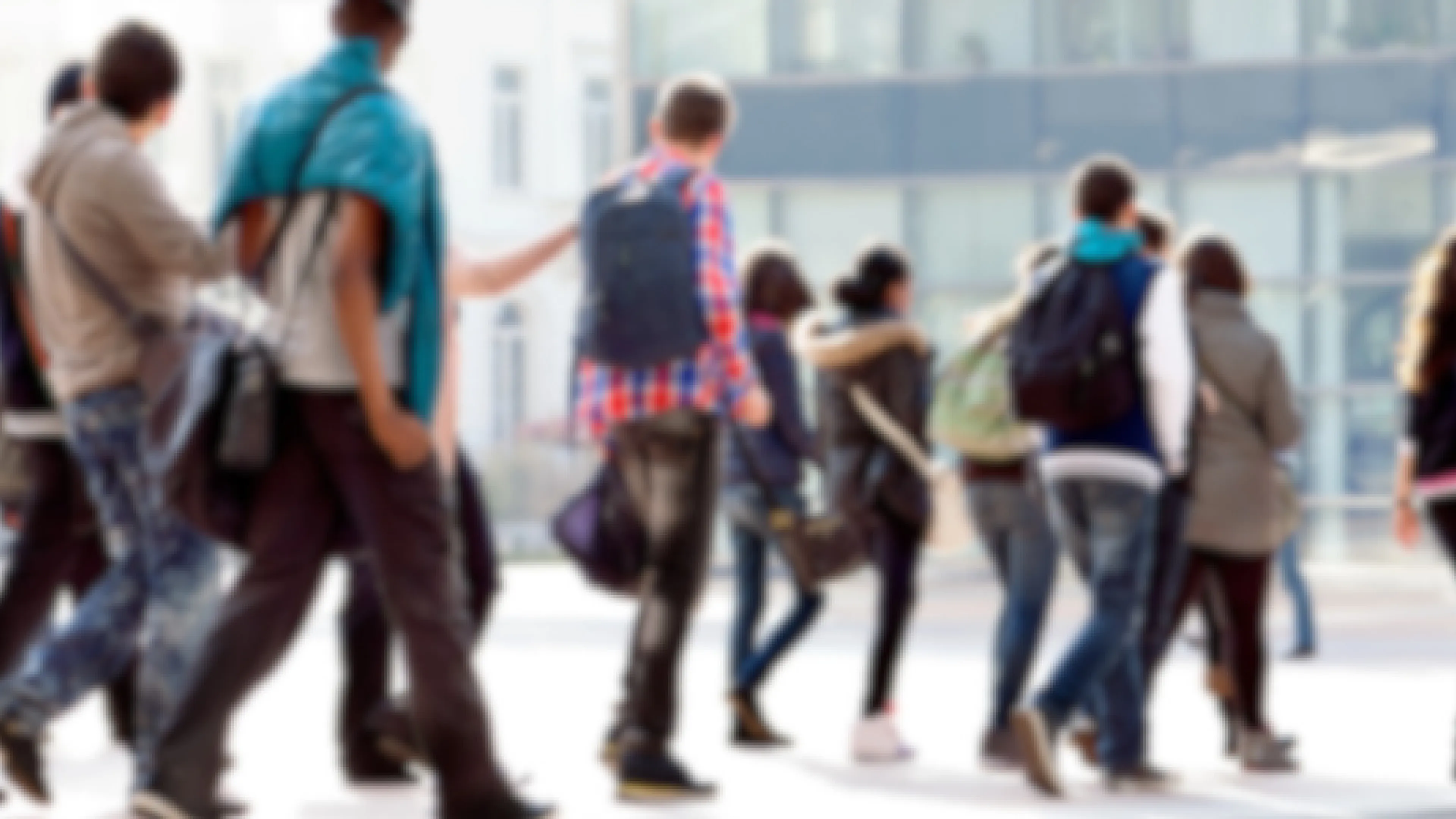 A blurry image of diverse young people outside walking away from the camera. You cannot see anyone's face.