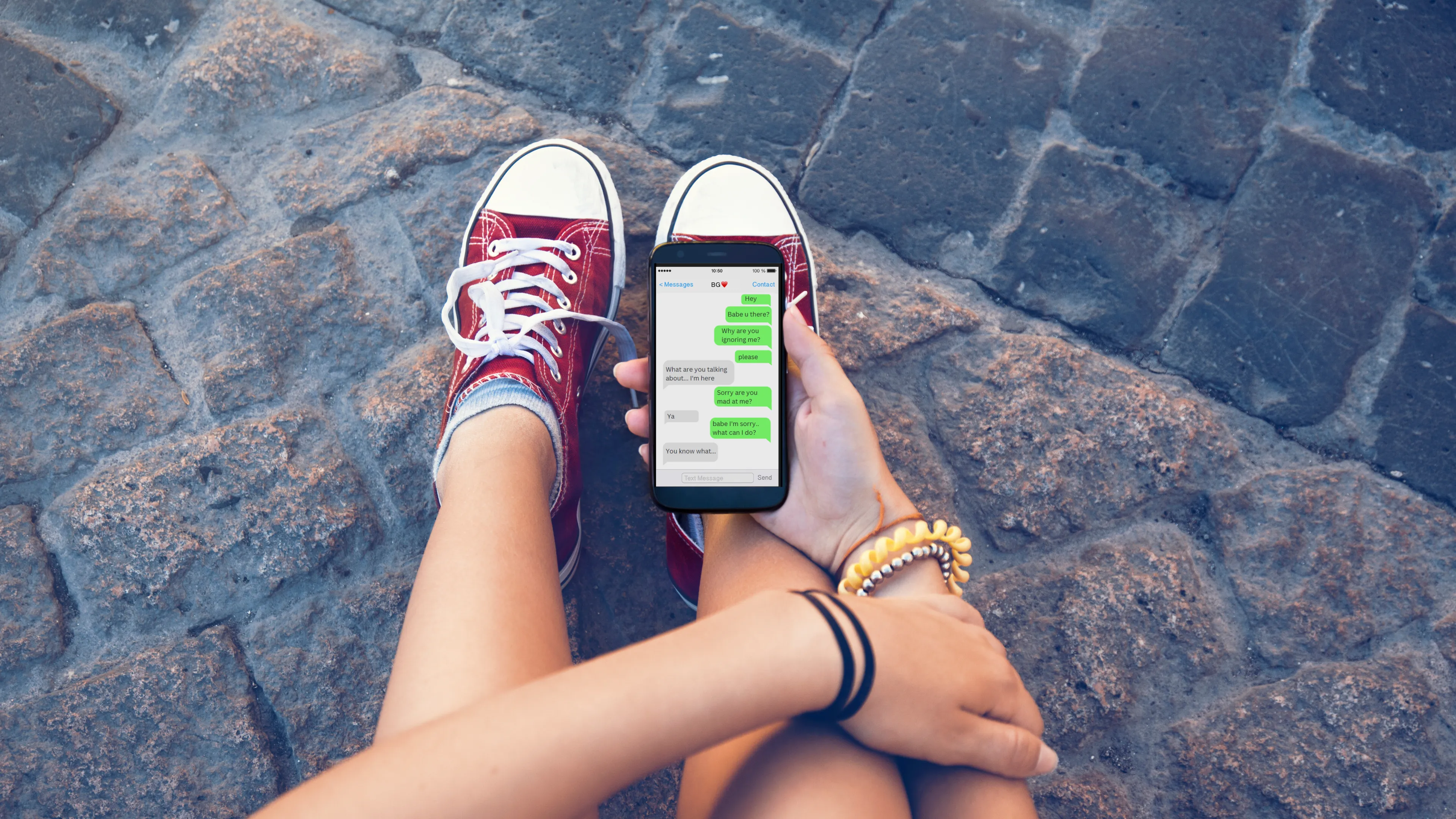 young person looking at phone. The phone screen shows text messages with someone who they are having an argument with.