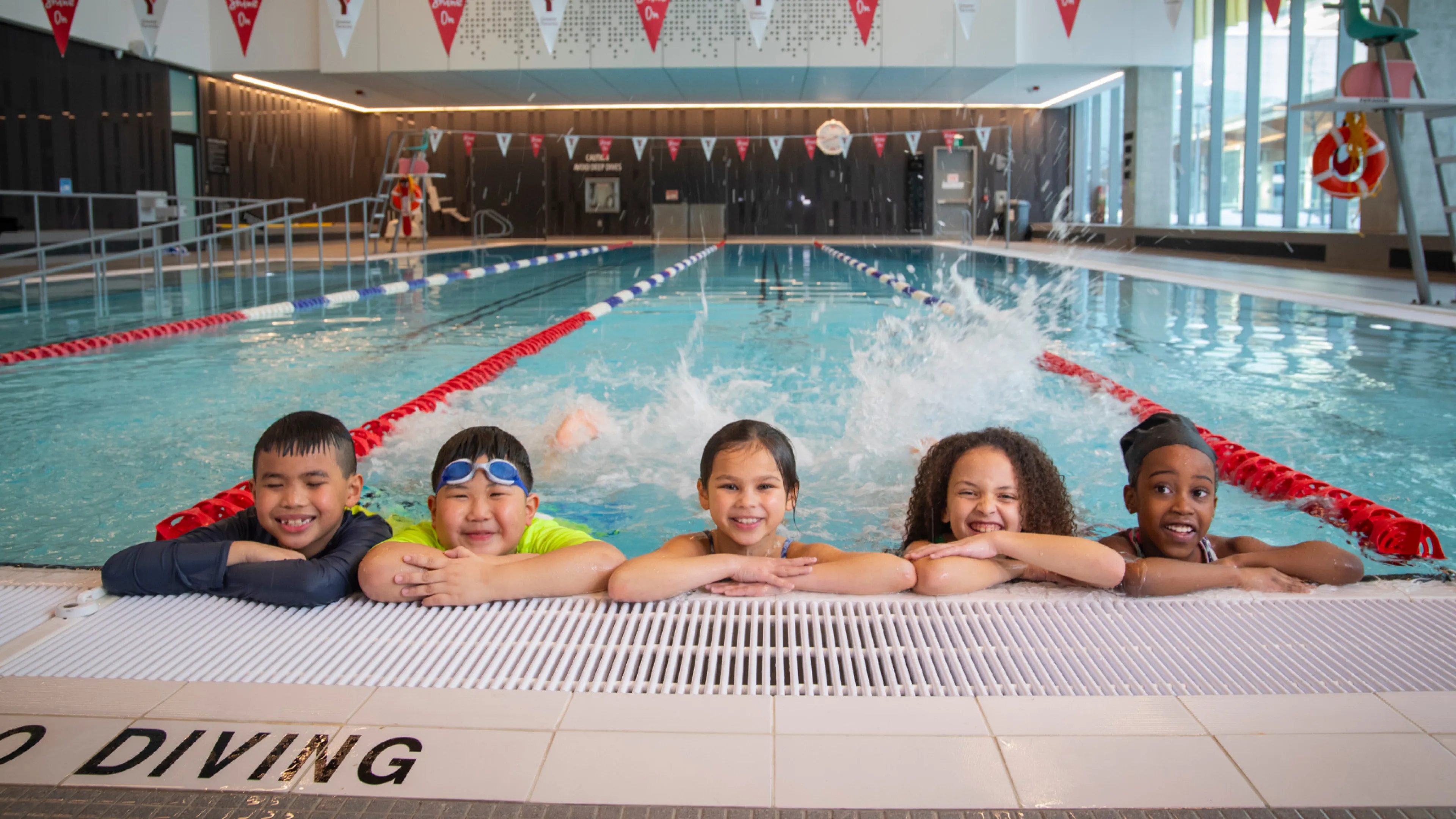 Five children in pool kicking feet and smiling