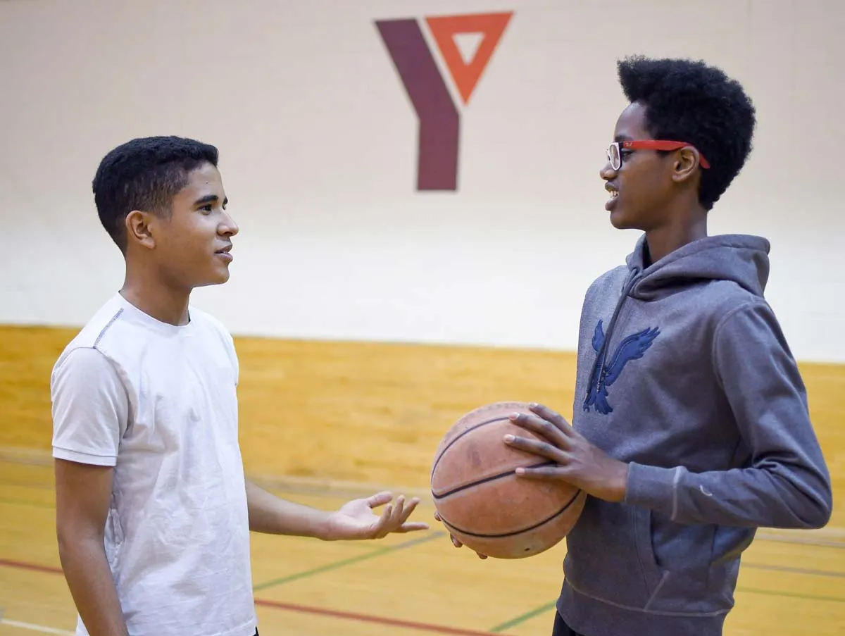 two youth talking while holding a basketball
