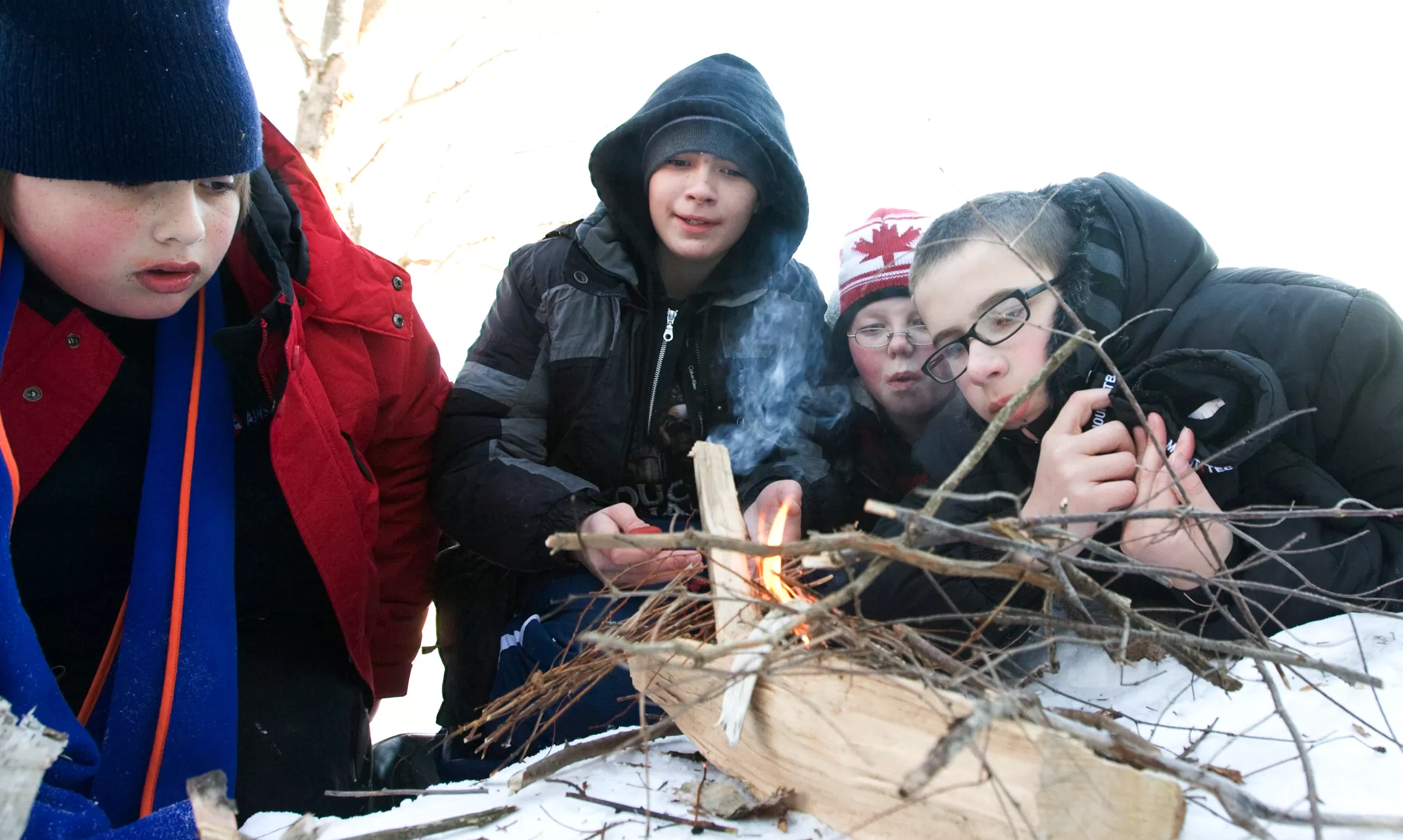 Four boys build a small campfire