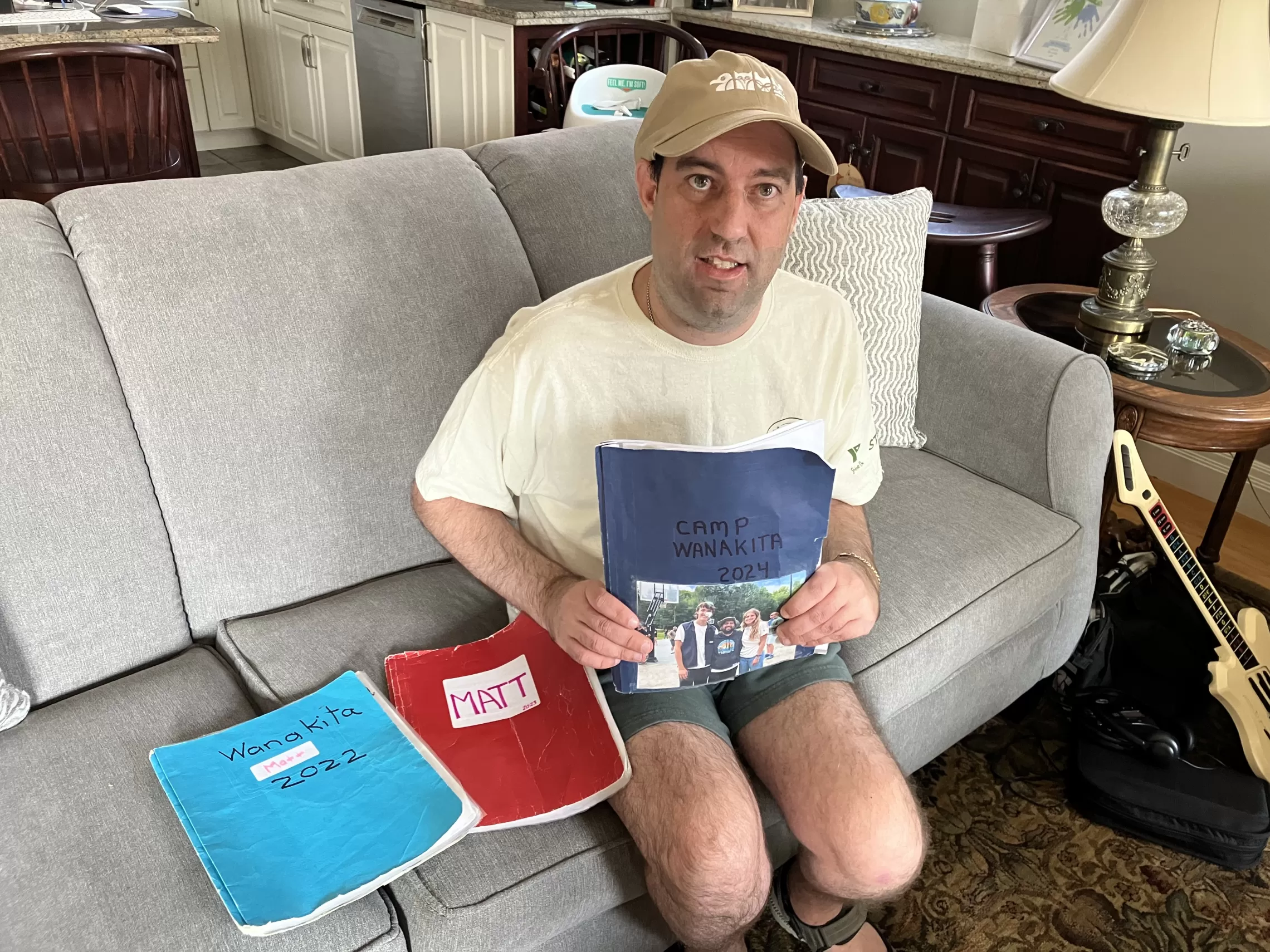 Matt Fox sitting on couch with his summer camp binders