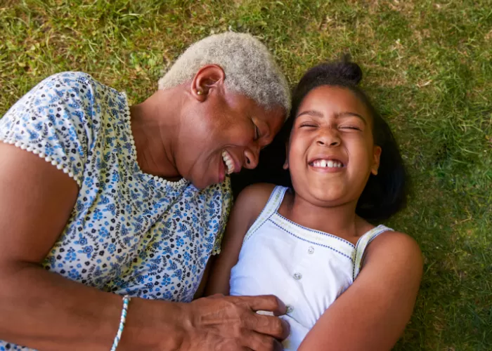Two individuals laying on the grass smiling and laughing