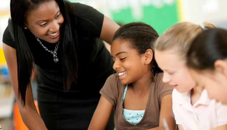 teacher speaking to student at desk