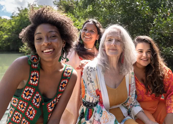 Four women sitting down looking into the camera and smiling